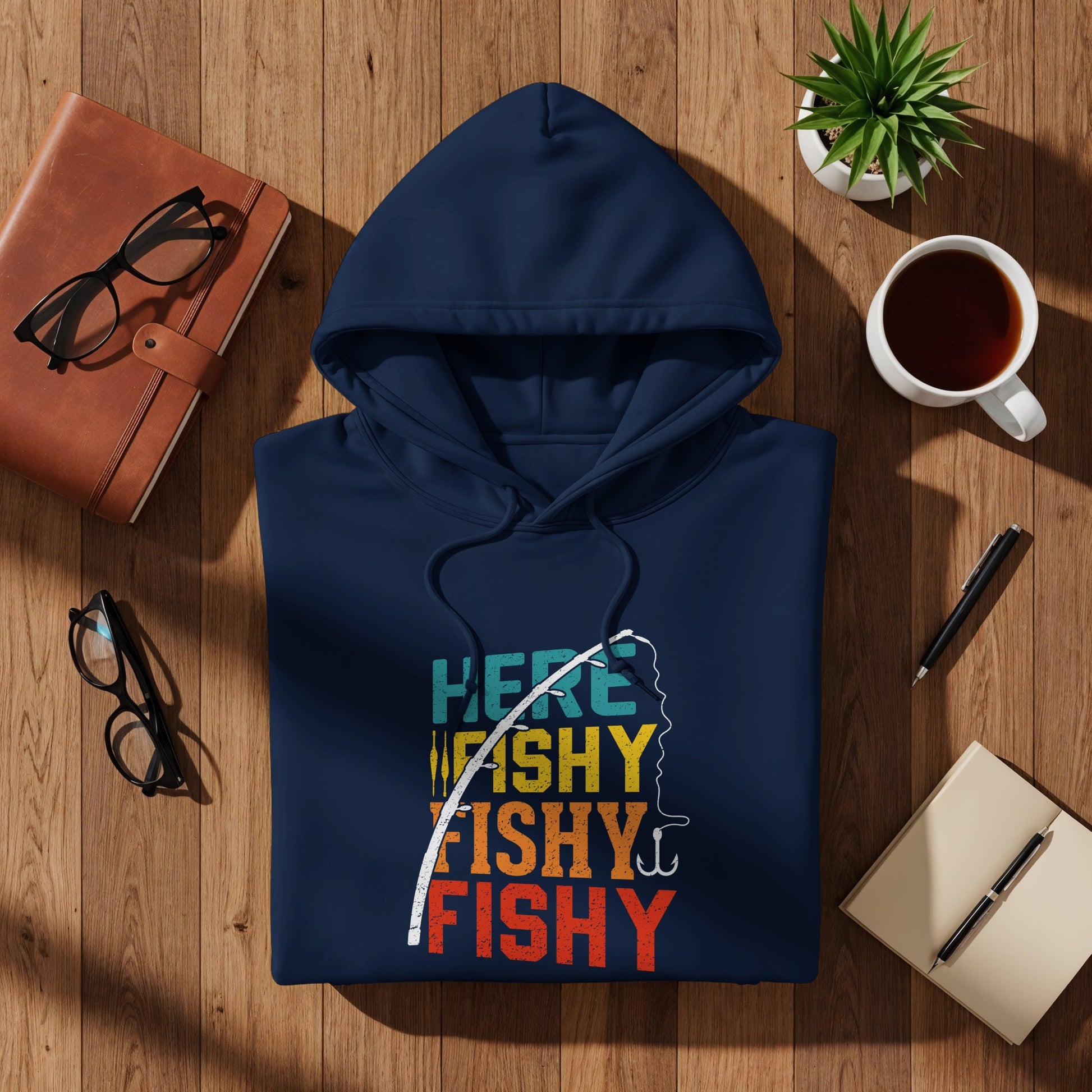 Navy hoodie with "Here Fishy Fishy" graphic, laid flat with accessories.