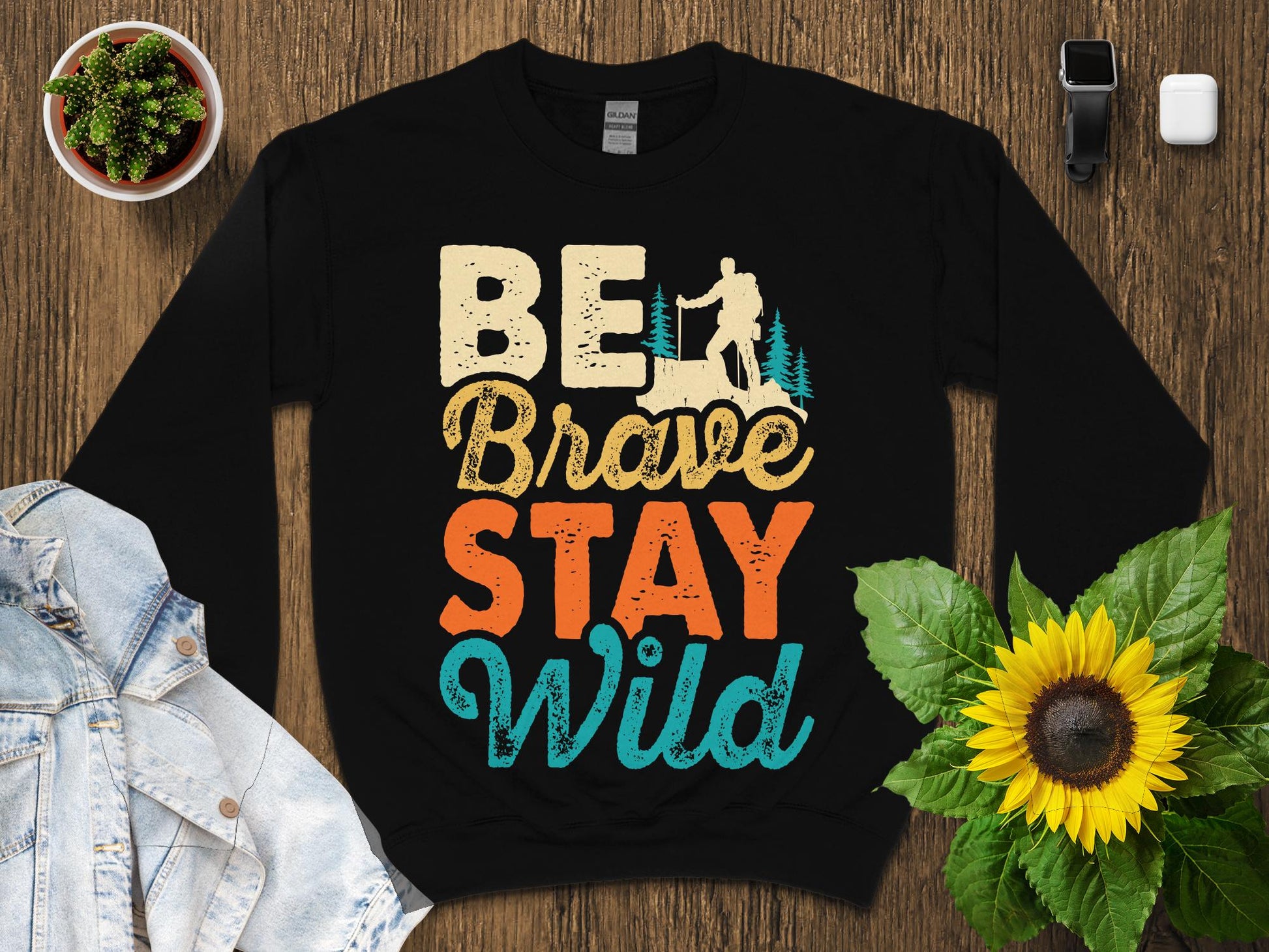 Black sweatshirt with "Be Brave Stay Wild" text and nature graphic.