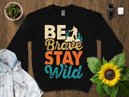 Black sweatshirt with "Be Brave Stay Wild" text and nature graphic.