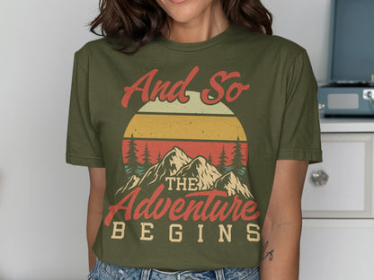 Olive green t-shirt with "And So The Adventure Begins" mountain sunset graphic.