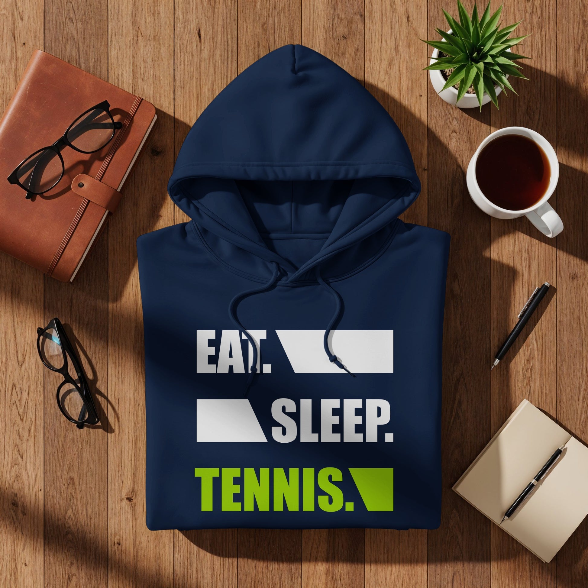 Navy blue hoodie with "EAT. SLEEP. TENNIS." graphic on a wooden surface.