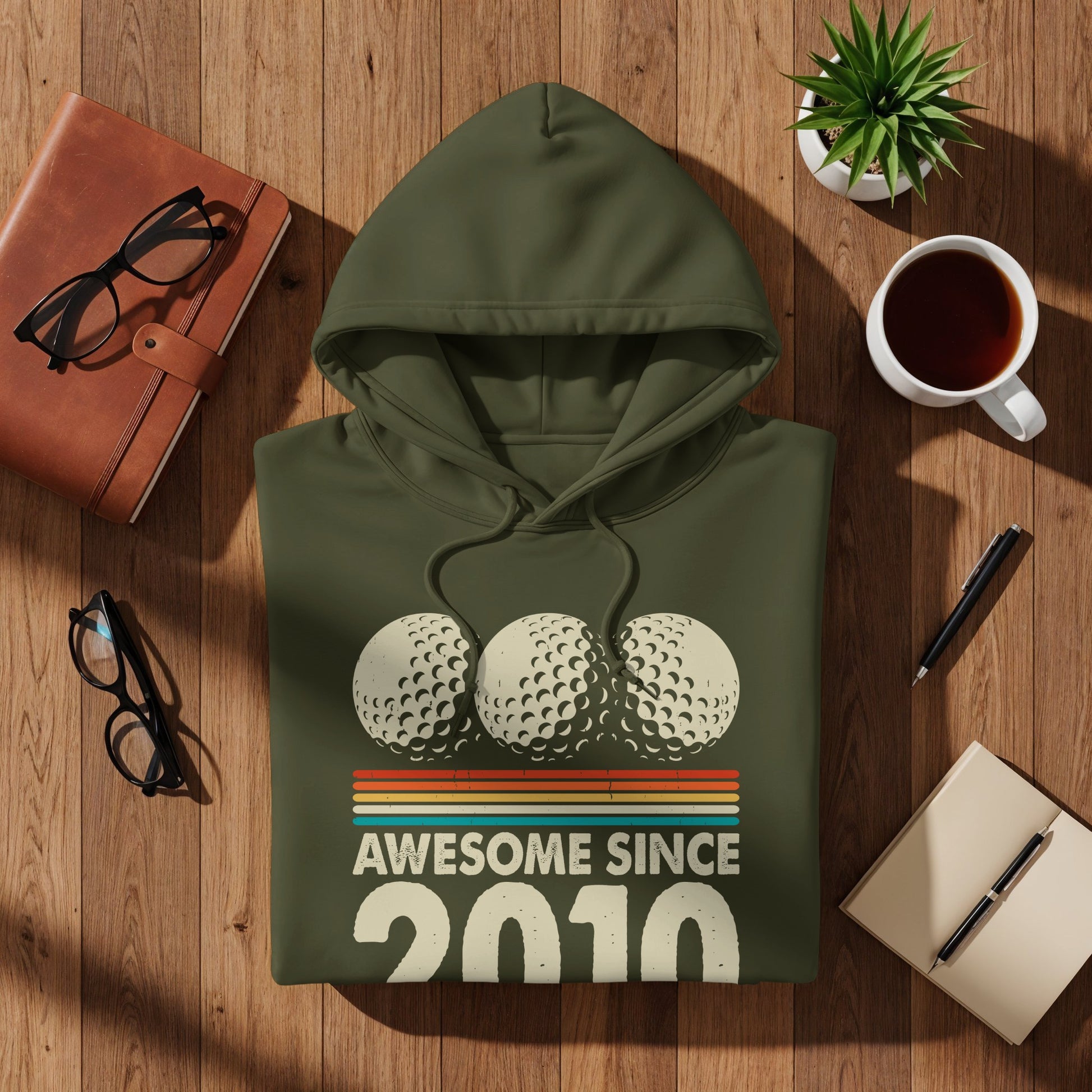 Olive green hoodie with "Awesome Since 2010" and three golf balls.