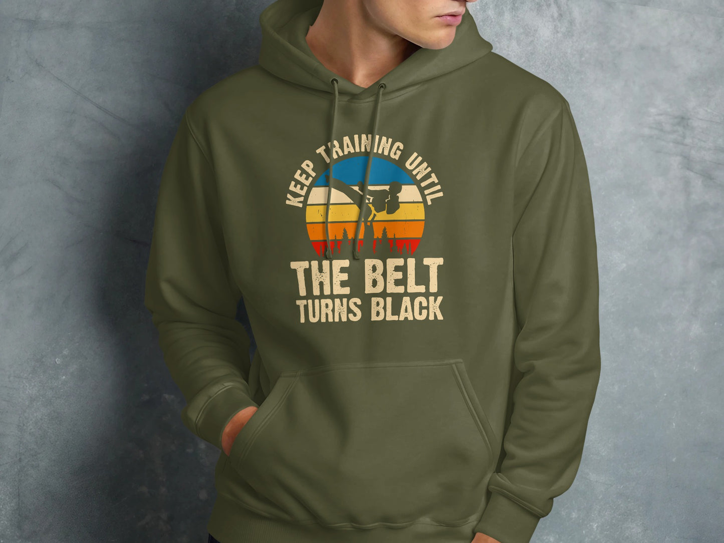 Green hoodie with "Keep training until the belt turns black" text and martial artist graphic.