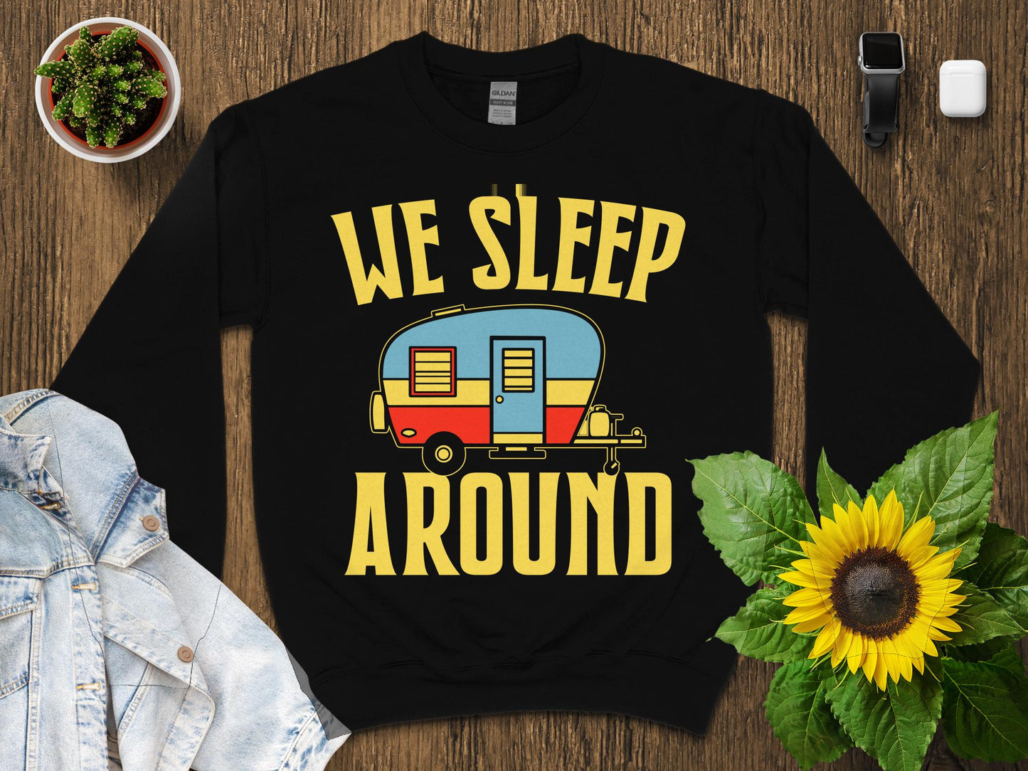 Black sweatshirt with yellow text "WE SLEEP AROUND" and a colorful vintage camper graphic.