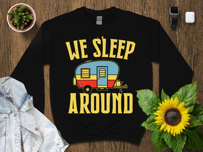 Black sweatshirt with yellow text "WE SLEEP AROUND" and a colorful vintage camper graphic.