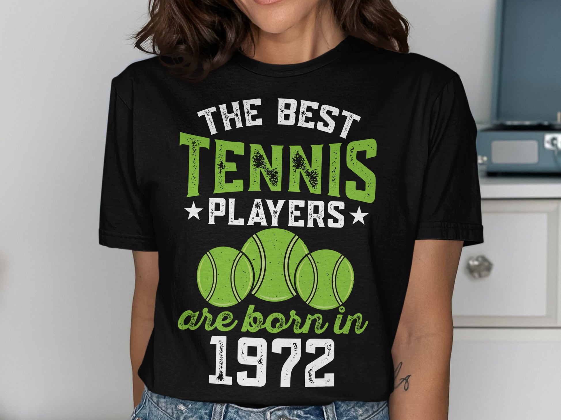 Black t-shirt with "The Best Tennis Players are Born in 1972" text and tennis balls.