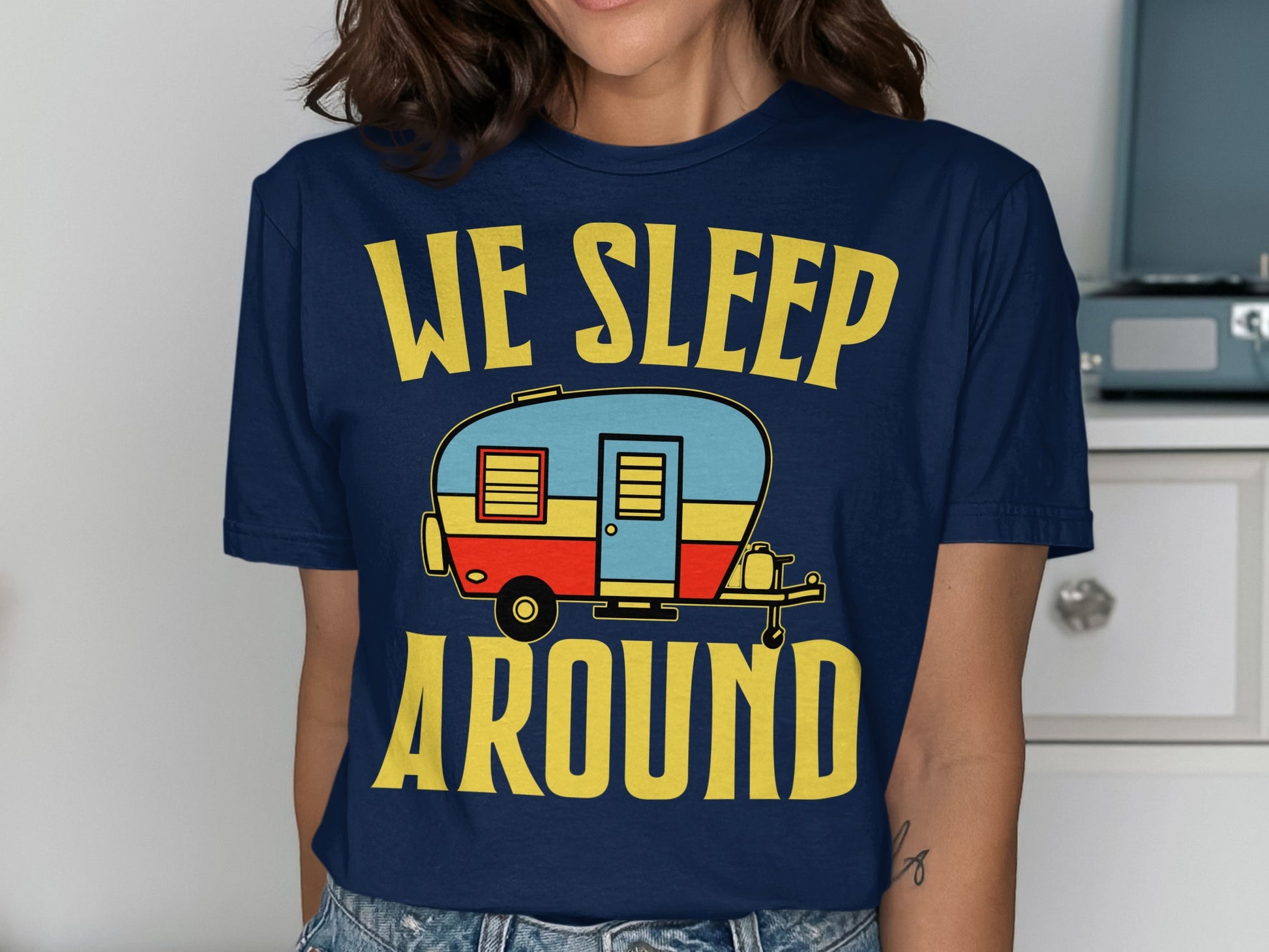 Dark blue t-shirt with "We Sleep Around" and a stylized camper graphic.