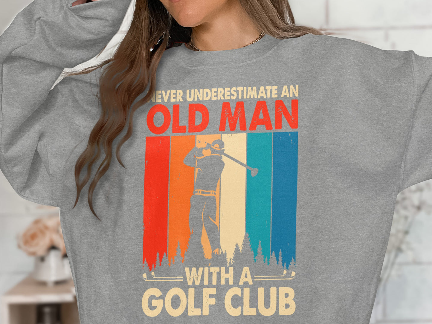 Gray sweatshirt with "Never Underestimate An Old Man With A Golf Club" and golfer graphic.