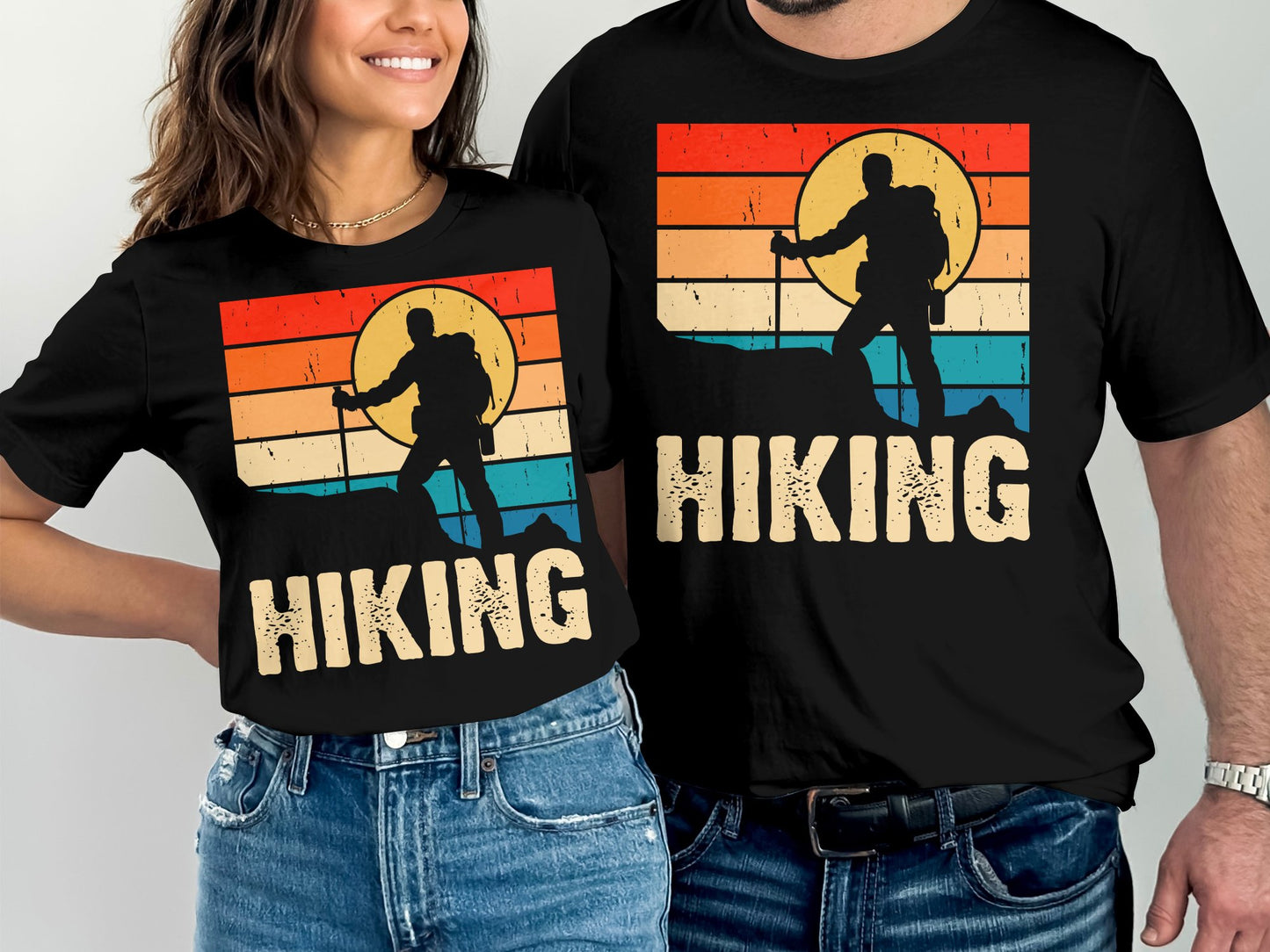 Two people wear matching t-shirts with a sunset hiking graphic and text.