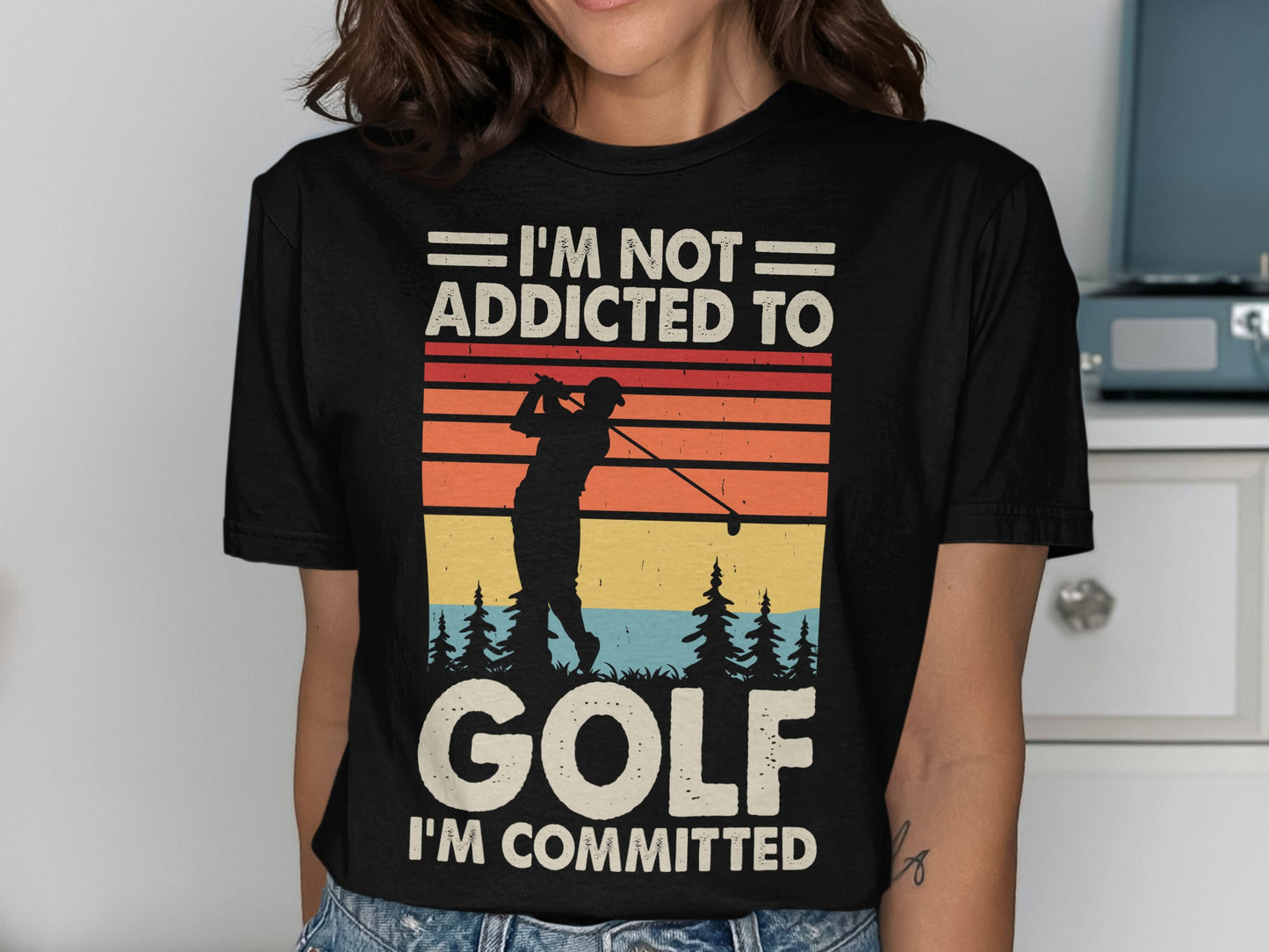 Black t-shirt with graphic of golfer and text "I'M NOT ADDICTED TO GOLF I'M COMMITTED".