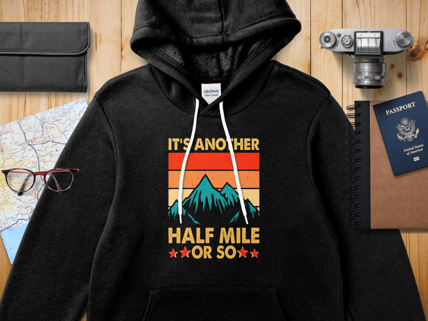 Black Gildan hoodie with "IT'S ANOTHER HALF MILE ★OR SO★" text and mountain graphic.