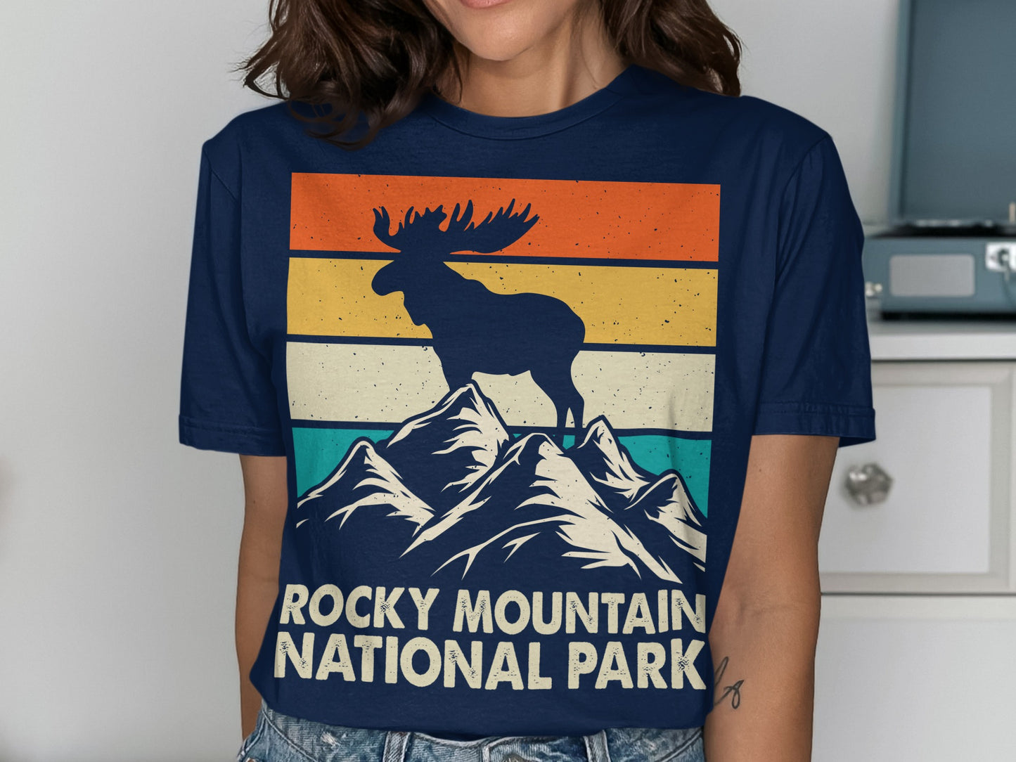 Moose on mountain peak with "Rocky Mountain National Park" text.