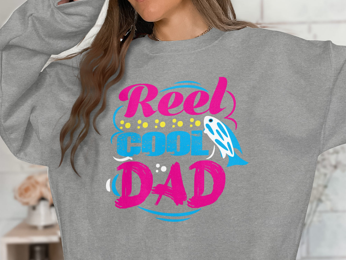 Grey sweatshirt with "Reel Cool Dad" text and a blue fish graphic.