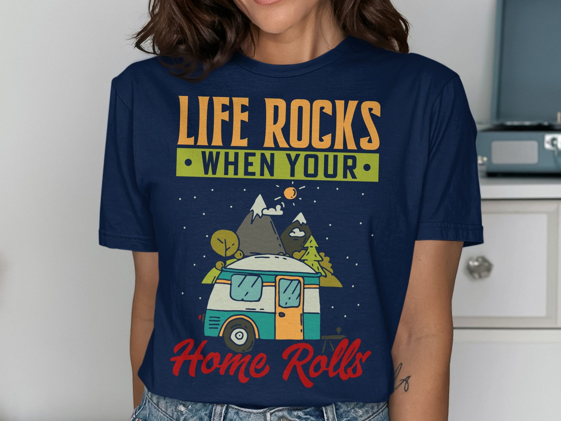 Dark blue t-shirt with "Life Rocks When Your Home Rolls" text and camper van illustration.