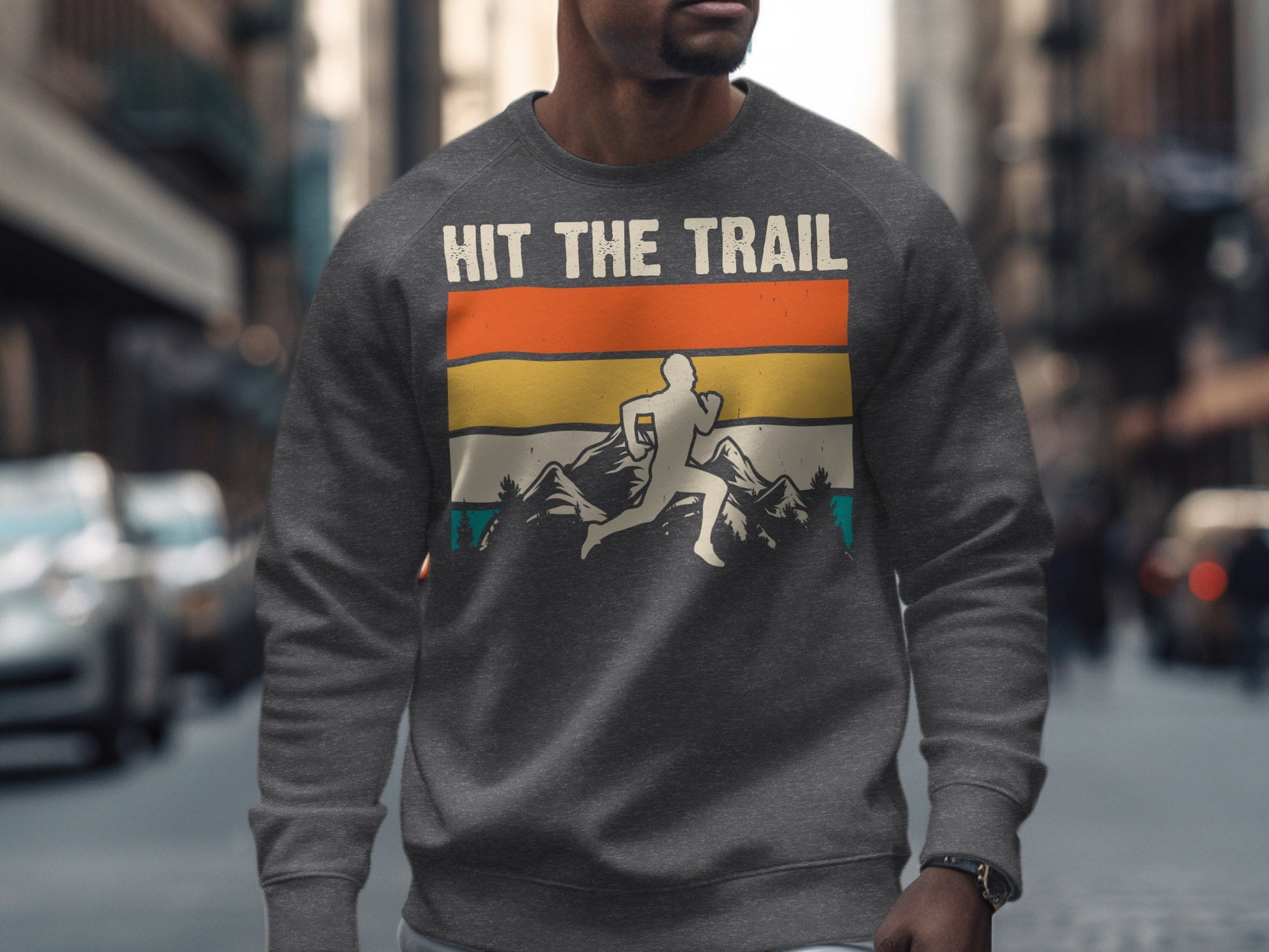 Man wearing a gray sweatshirt with "Hit the Trail" graphic featuring a runner and mountain landscape.