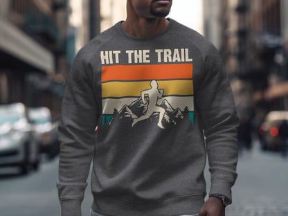 Man wearing a gray sweatshirt with "Hit the Trail" graphic featuring a runner and mountain landscape.
