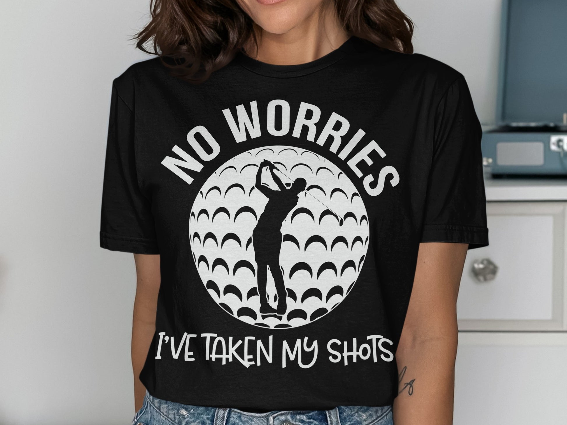 Black t-shirt with golfer silhouette, golf ball pattern, and text "NO WORRIES I'VE TAKEN MY SHOTS".