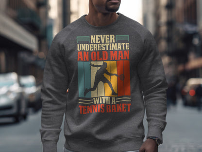 Grey sweatshirt with graphic of a tennis player and text "Never underestimate an old man with a tennis racket."