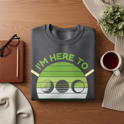 Dark grey sweatshirt with green graphic of golf balls and text "I'm here to".