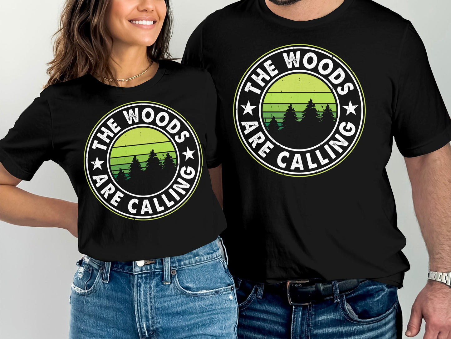 Two black t-shirts with "The Woods Are Calling" text and forest graphic.