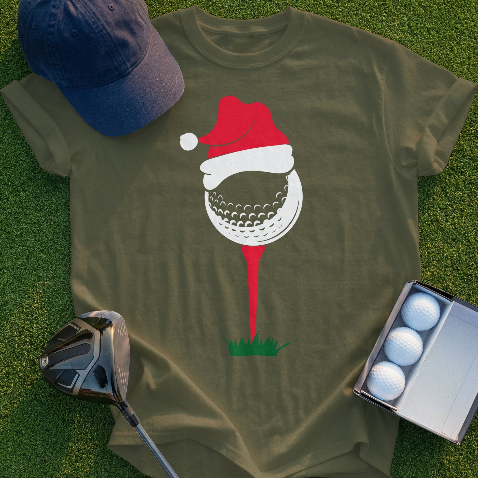 Golf ball with Santa hat on tee, green grass background, golf club and balls.