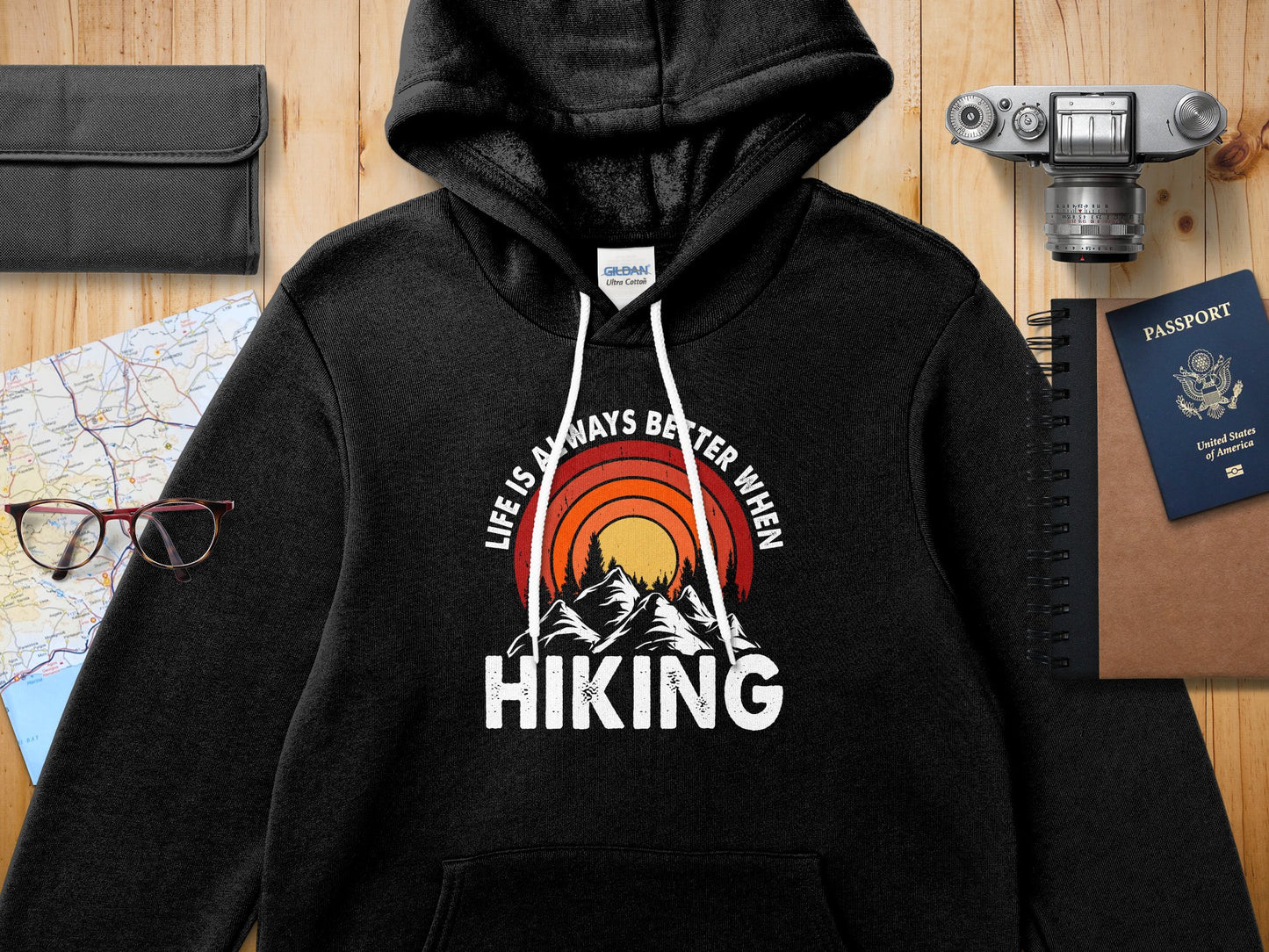 Black hoodie with "Life is always better when hiking" graphic featuring mountains and sun.