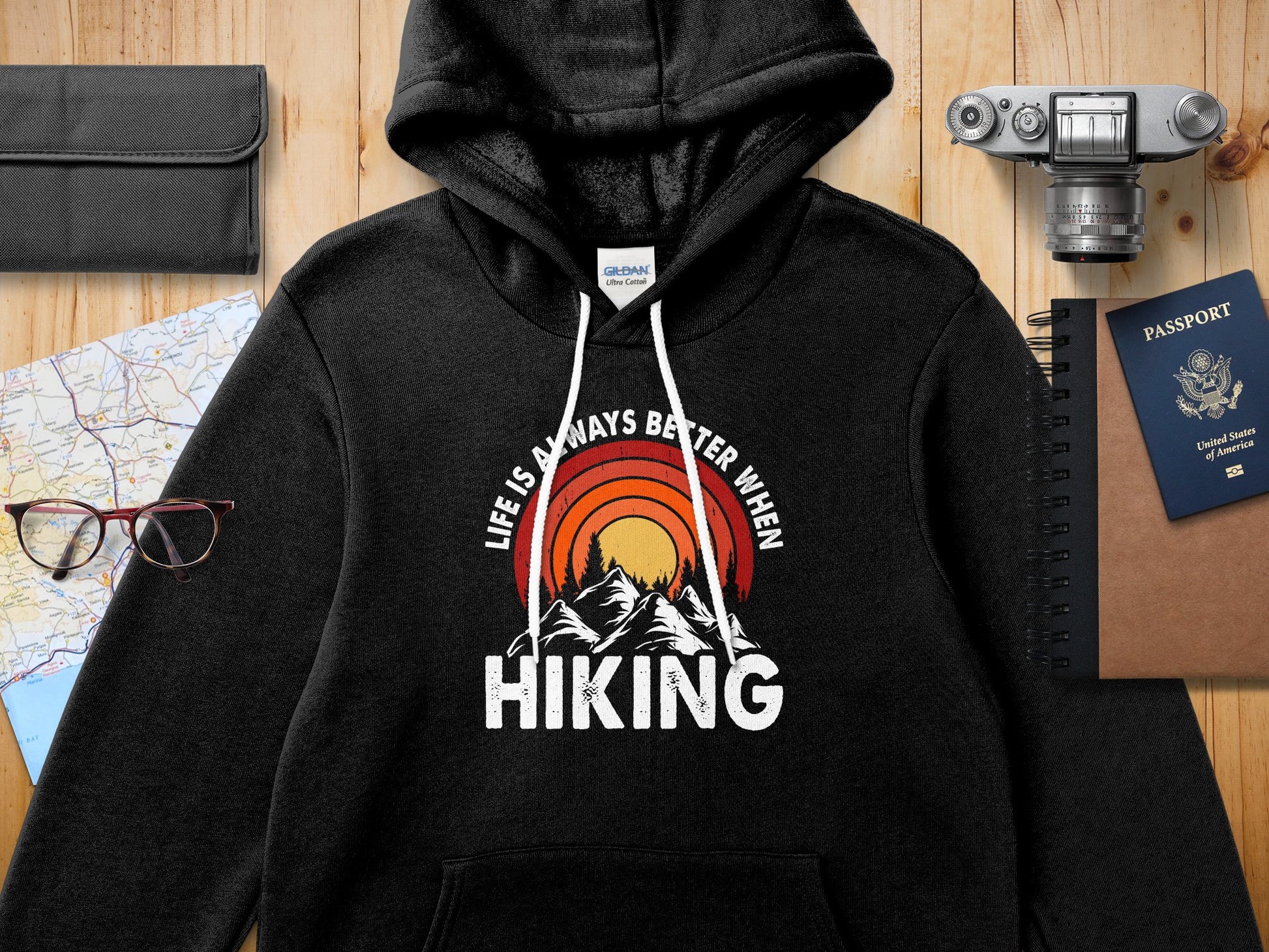 Black hoodie with "Life is always better when hiking" graphic featuring mountains and sun.