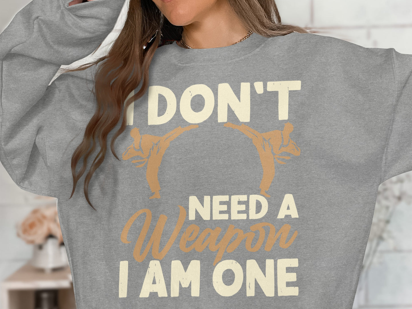 Gray sweatshirt with "I DON'T NEED A WEAPON I AM ONE" text and martial arts figures.