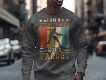 Men's dark gray sweatshirt with "I am a tennis coach, not a target" text.