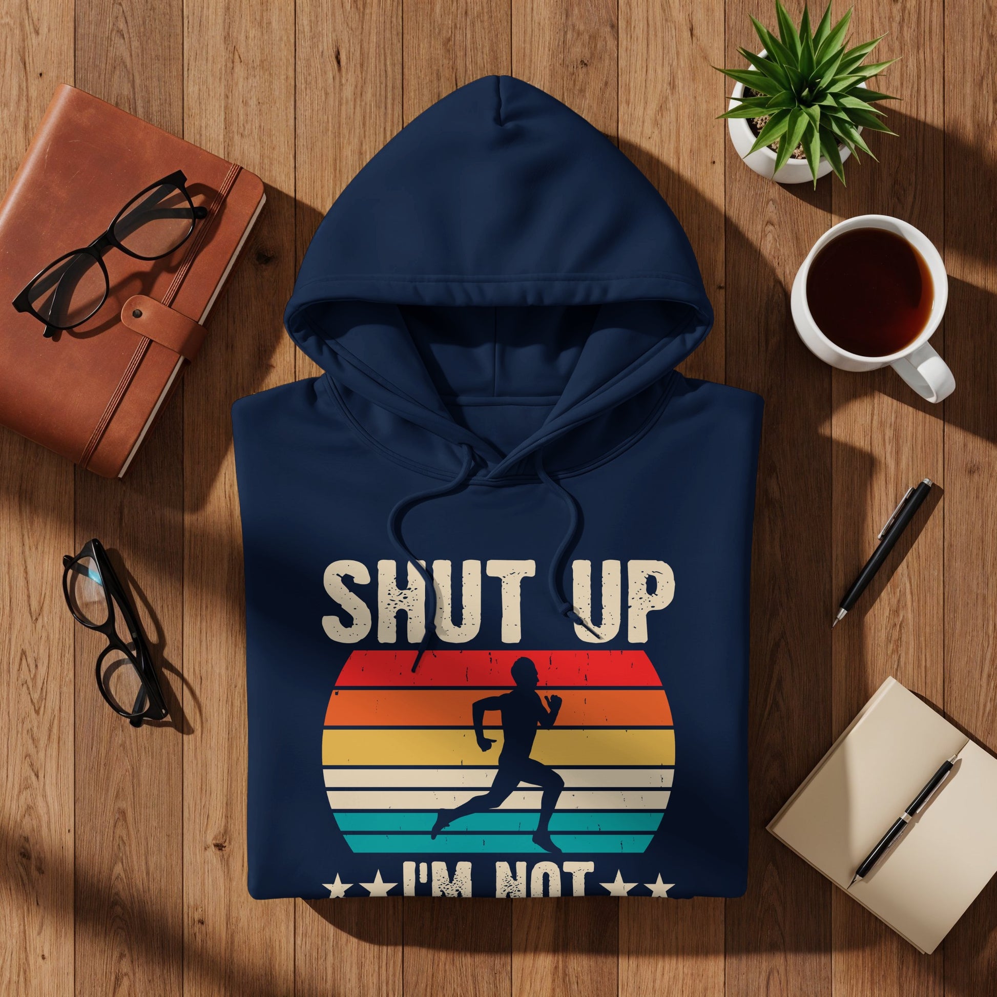 Navy hoodie with "SHUT UP I'M NOT RUNNING" text and vintage sunset runner graphic.