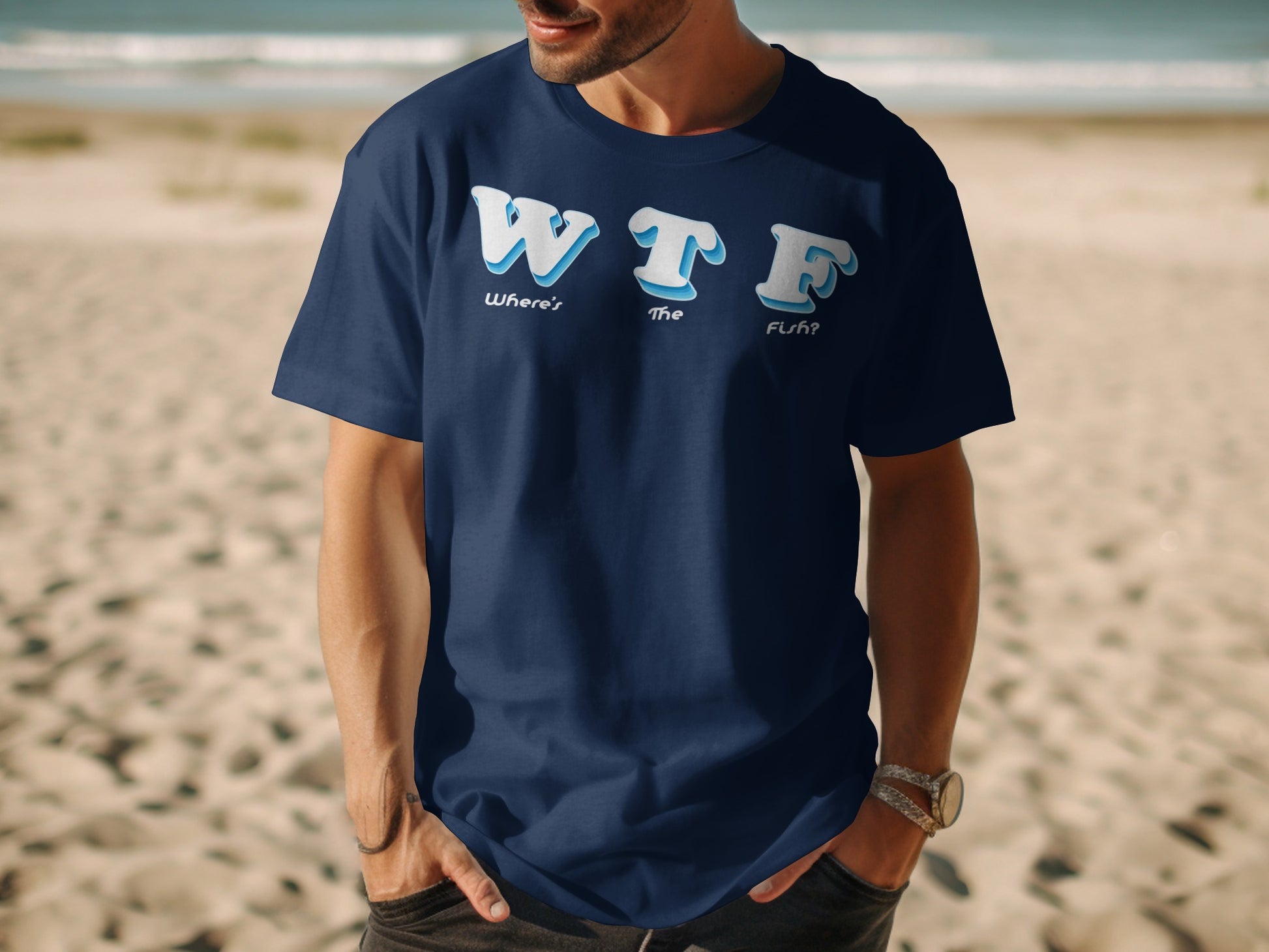 Navy t-shirt with "WTF Where's The Fish?" text on a sandy beach.