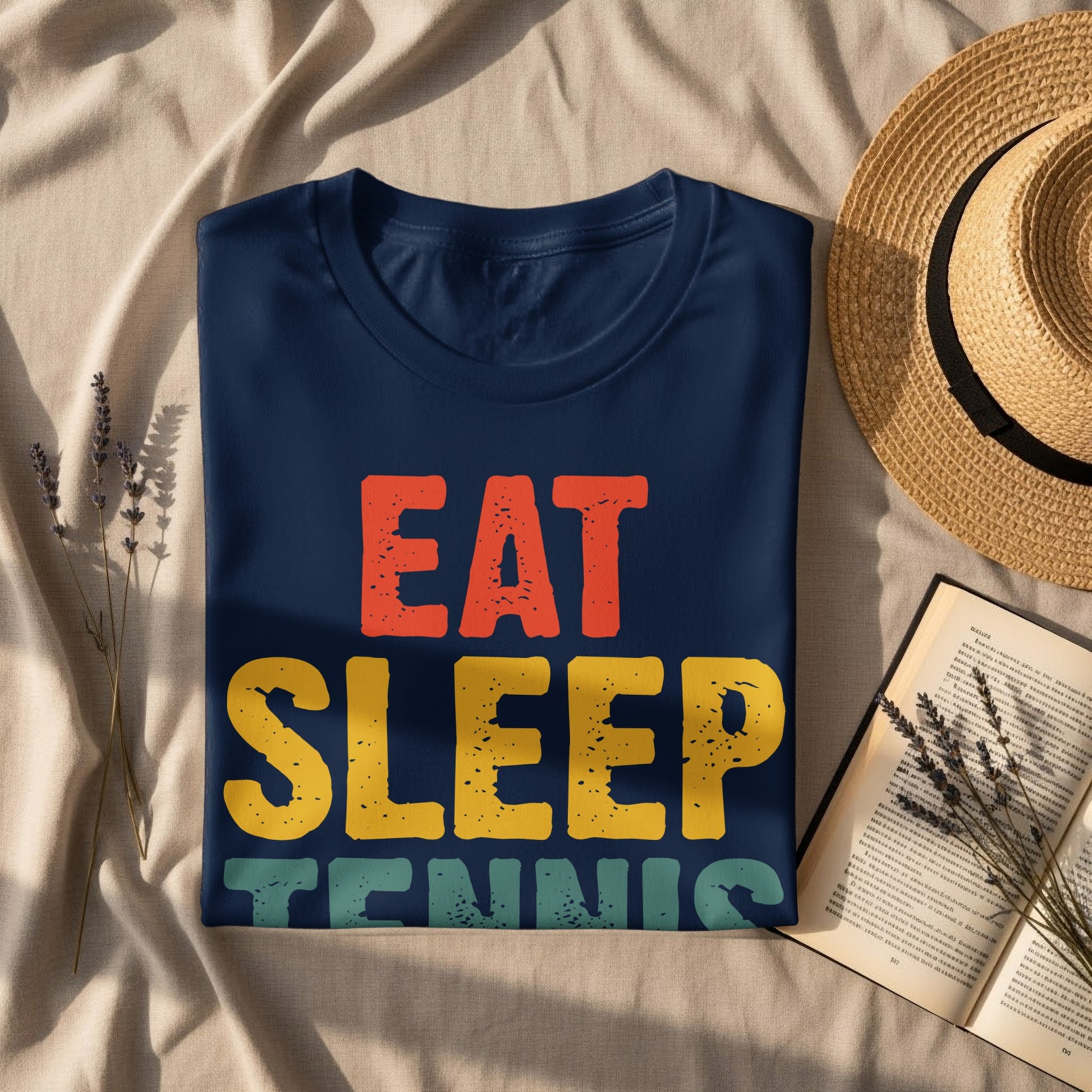 Navy t-shirt with "EAT SLEEP TENNIS" graphic, with a book and hat.