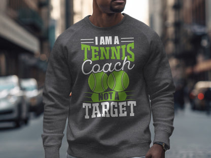 Grey sweatshirt with text "I AM A TENNIS COACH NOT A TARGET" and two green tennis balls.
