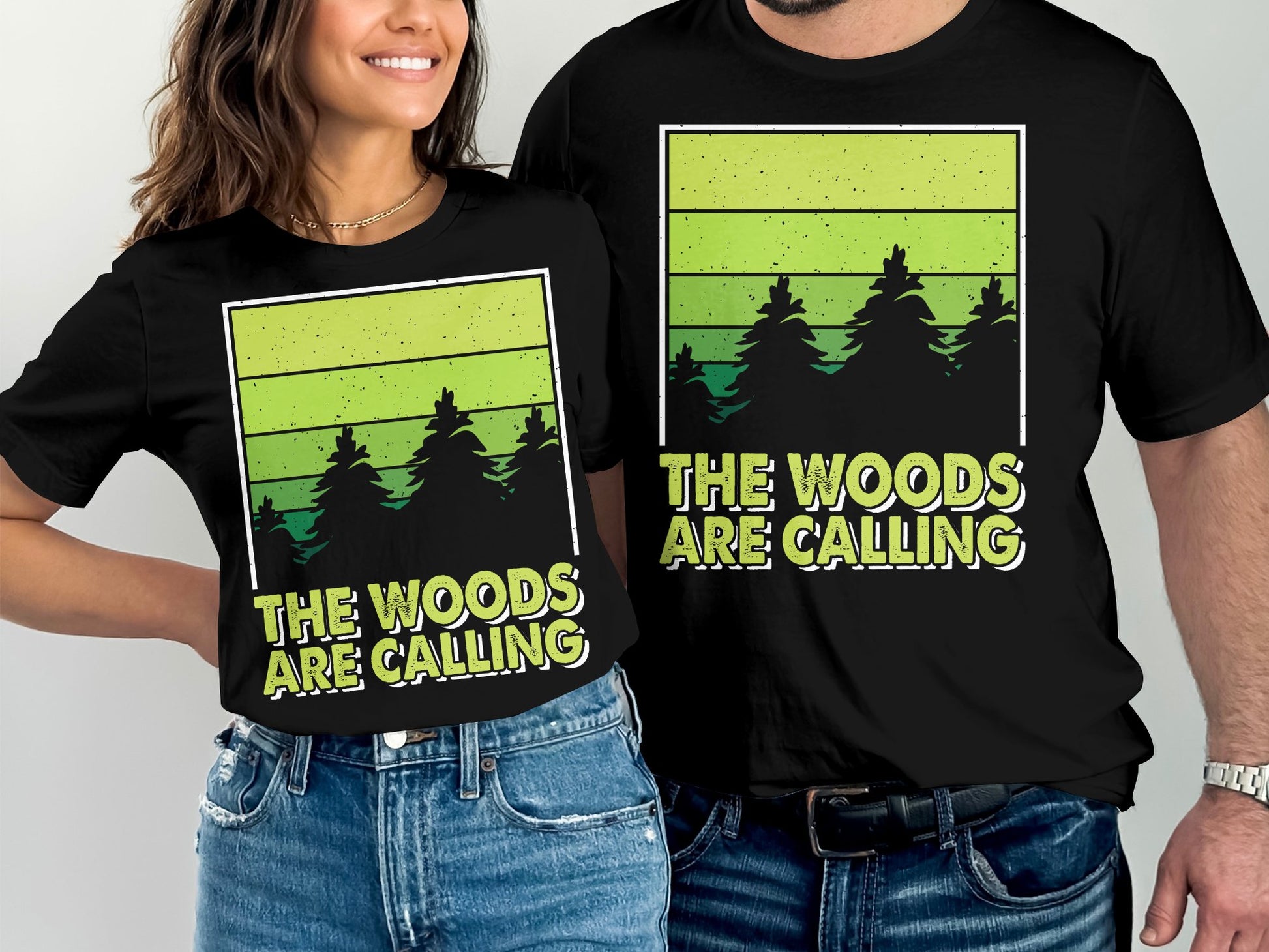Couple wearing black t-shirts with "The Woods Are Calling" forest design.
