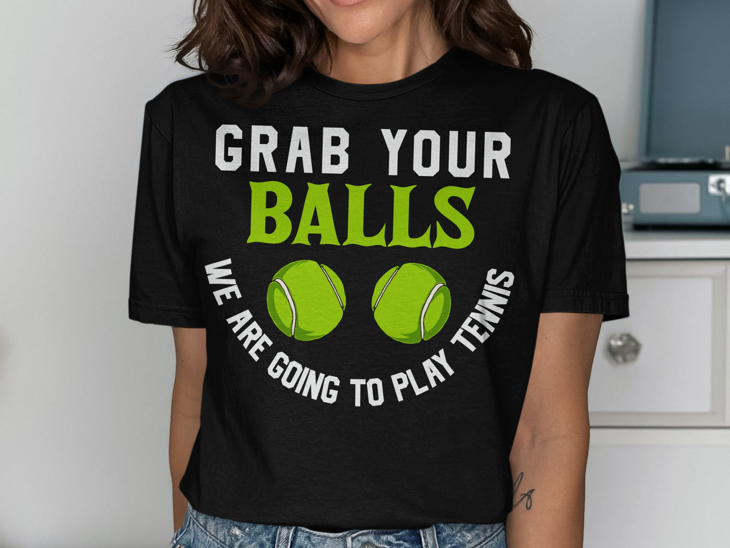 Black t-shirt with white text "GRAB YOUR BALLS" and green tennis balls.