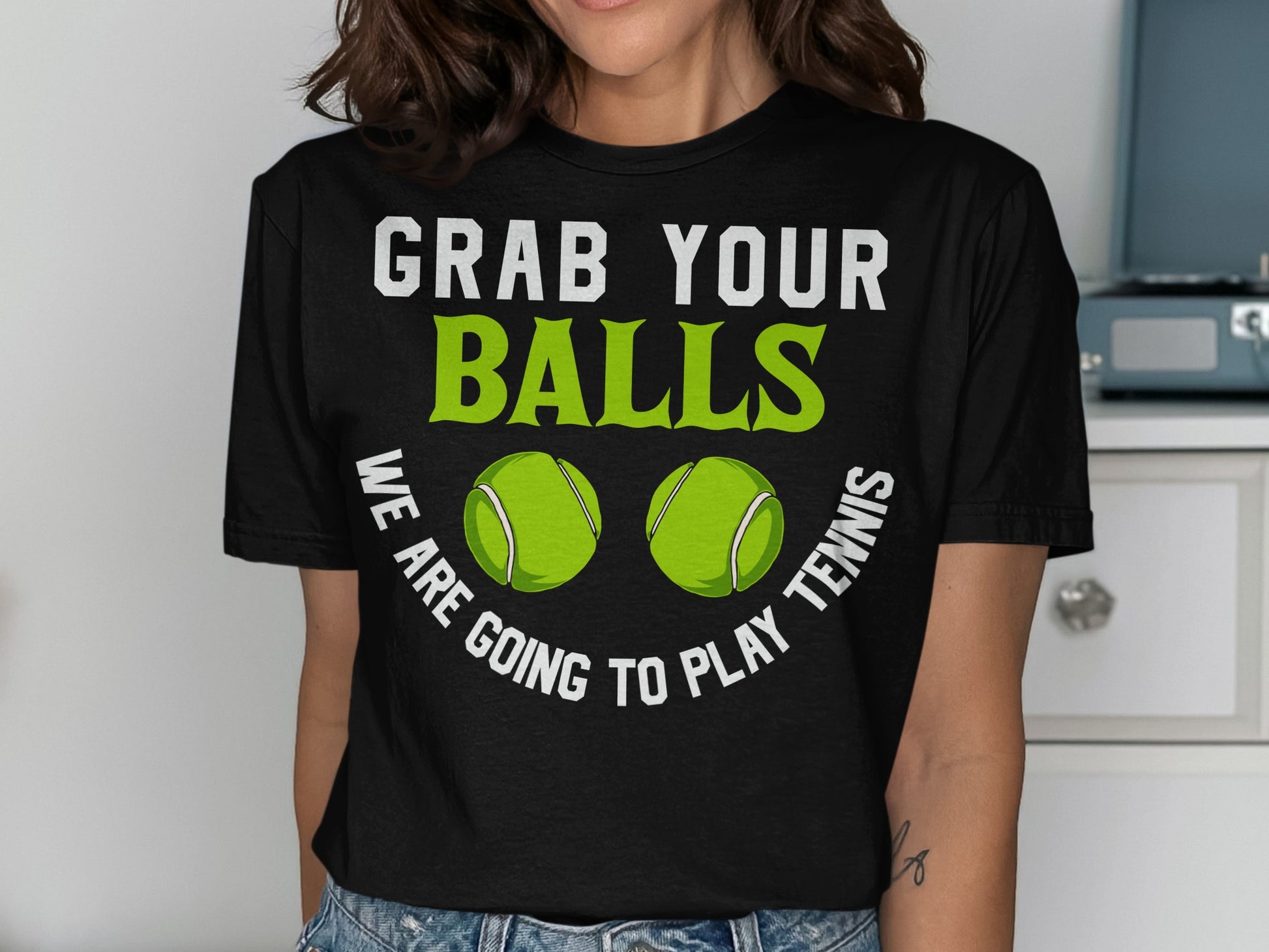 Black t-shirt with white text "GRAB YOUR BALLS" and green tennis balls.