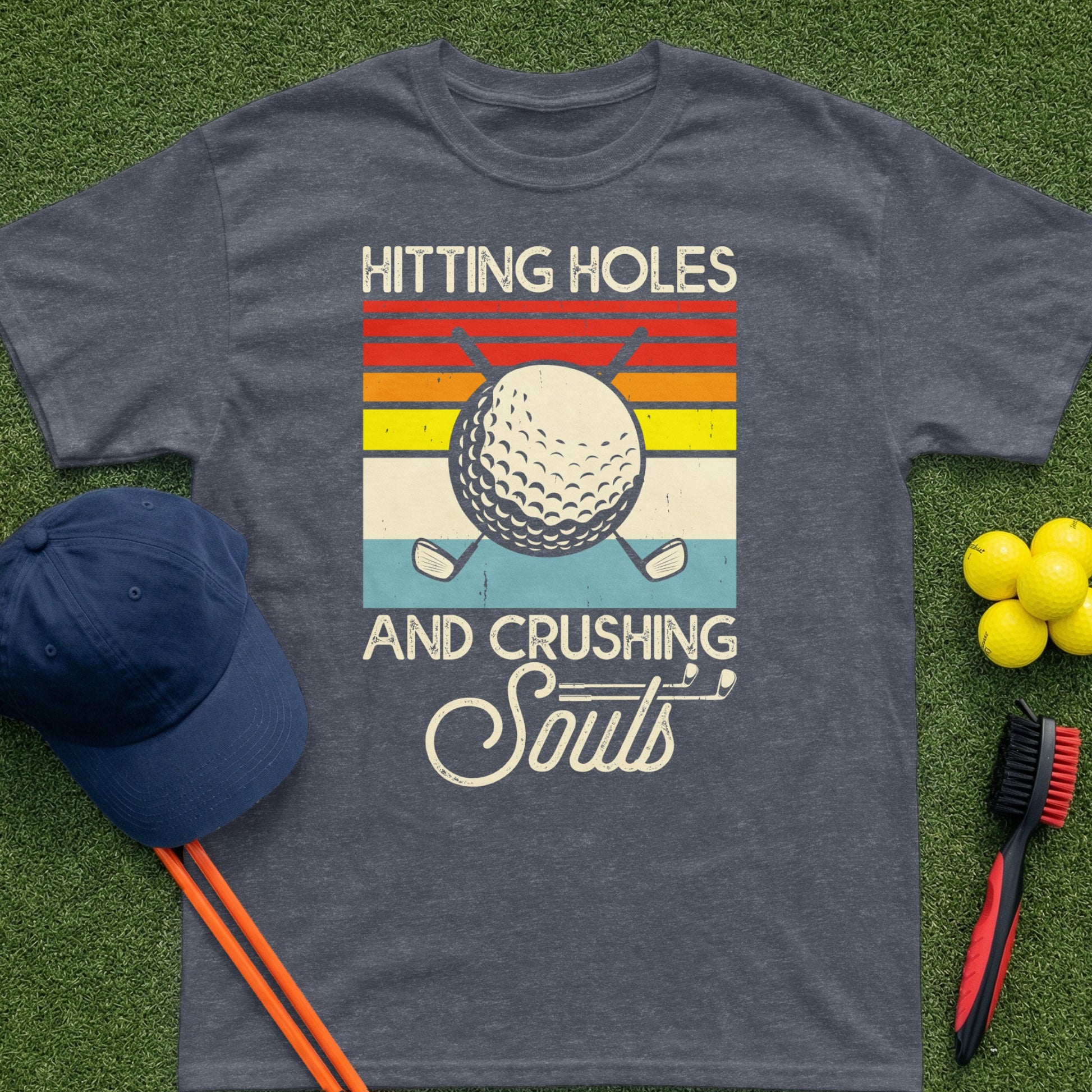 Dark grey t-shirt with vintage golf balls and text "HITTING HOLES AND CRUSHING SOULS".