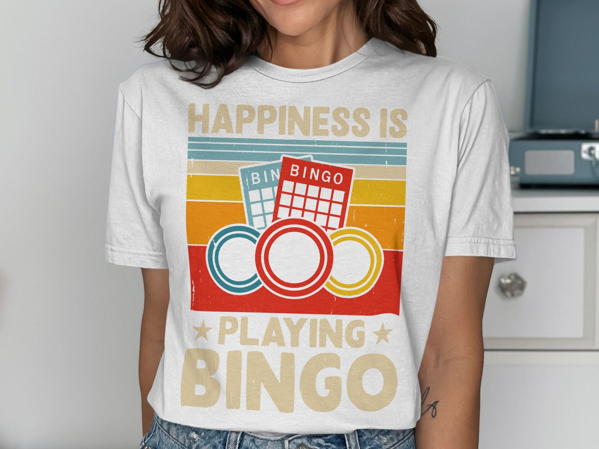 "Happiness is playing Bingo" text on a t-shirt with bingo cards and chips.