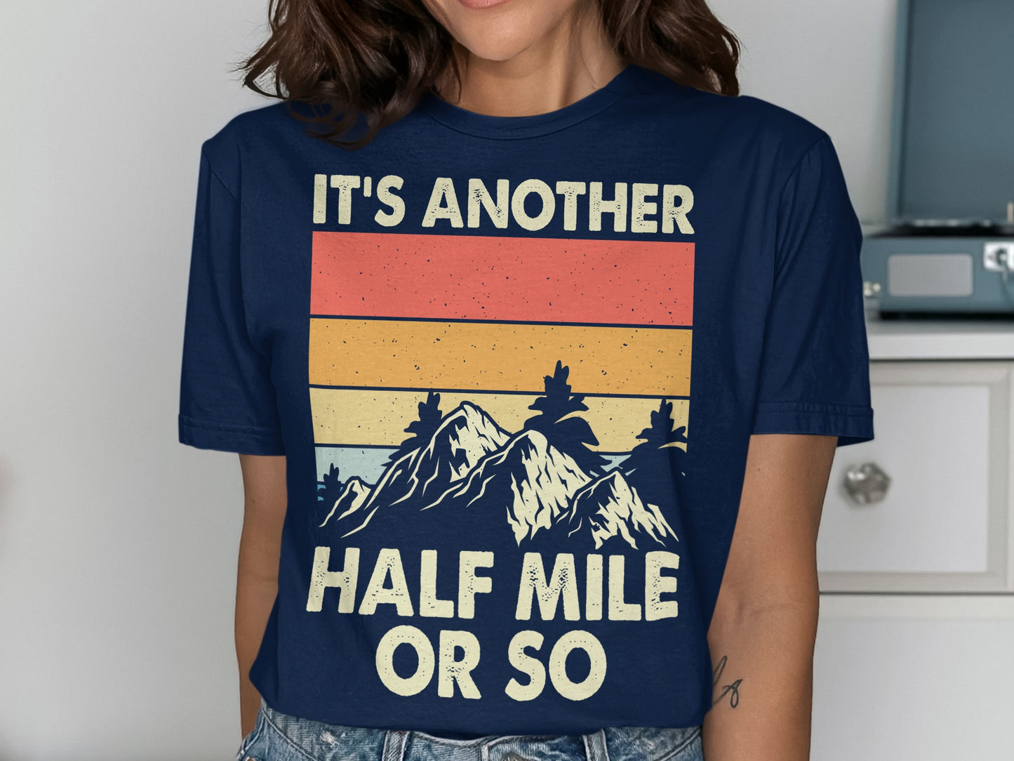Navy t-shirt with striped mountain graphic and text "IT'S ANOTHER HALF MILE OR SO".