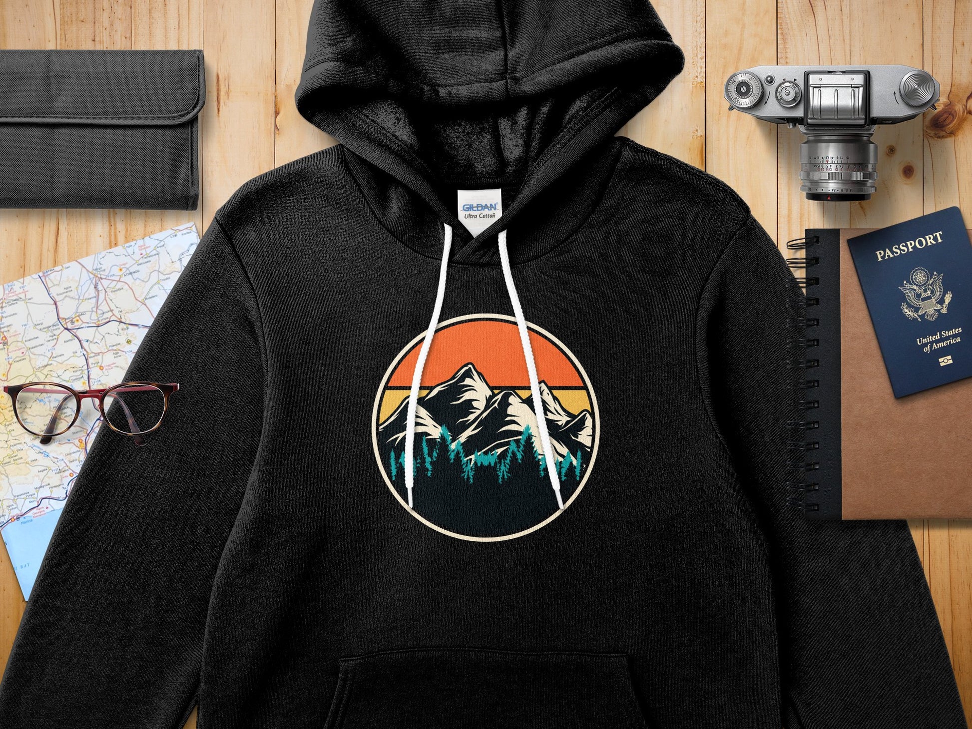 Black hooded sweatshirt with a circular mountain and forest graphic.