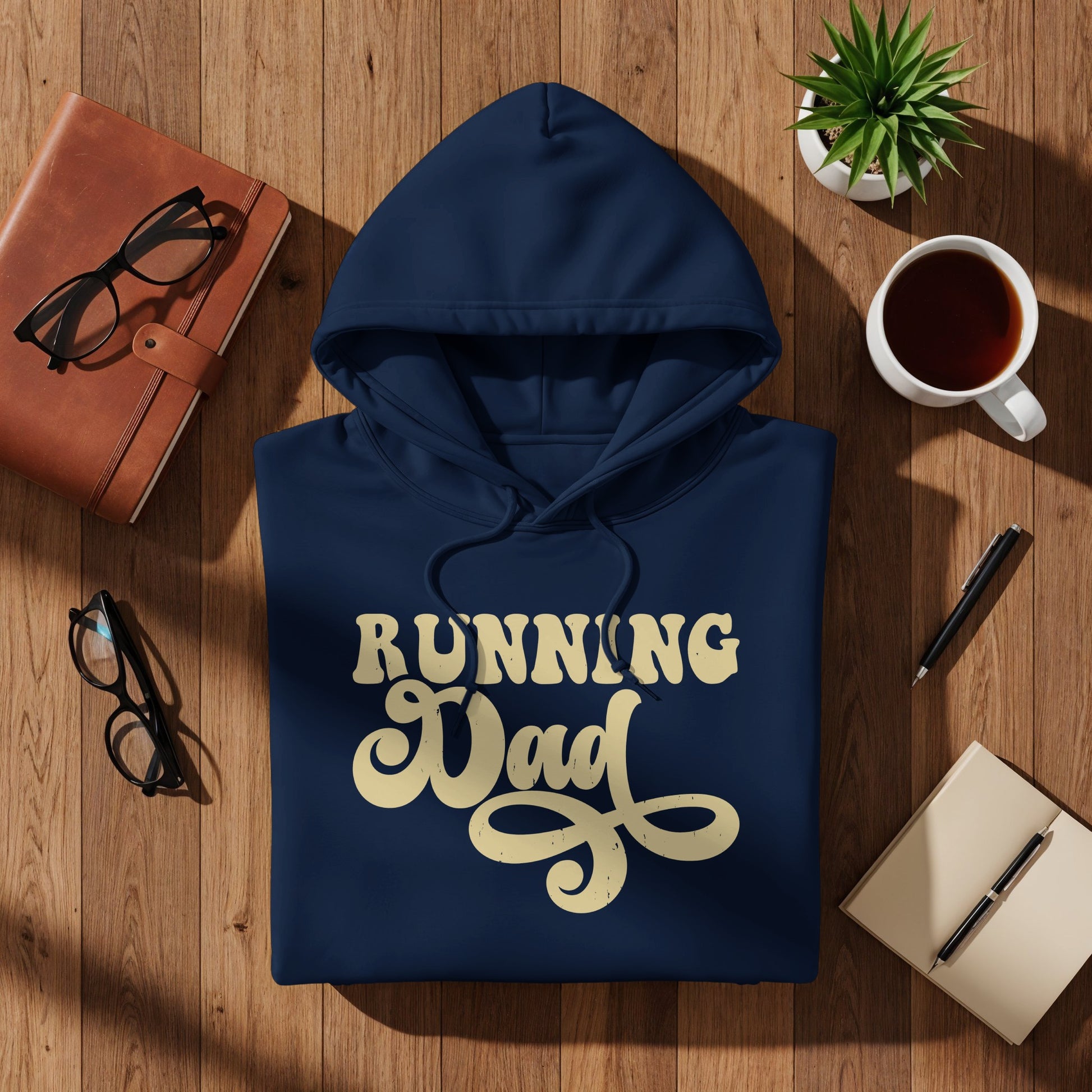 Navy blue hoodie with "Running Dad" text, on a wooden surface.