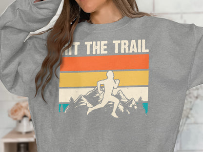 Gray sweatshirt with runner, mountains, and "HIT THE TRAIL" text.