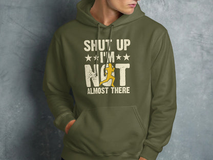 Olive green hoodie with "SHUT UP I'M NOT ALMOST THERE" text and runner graphic.