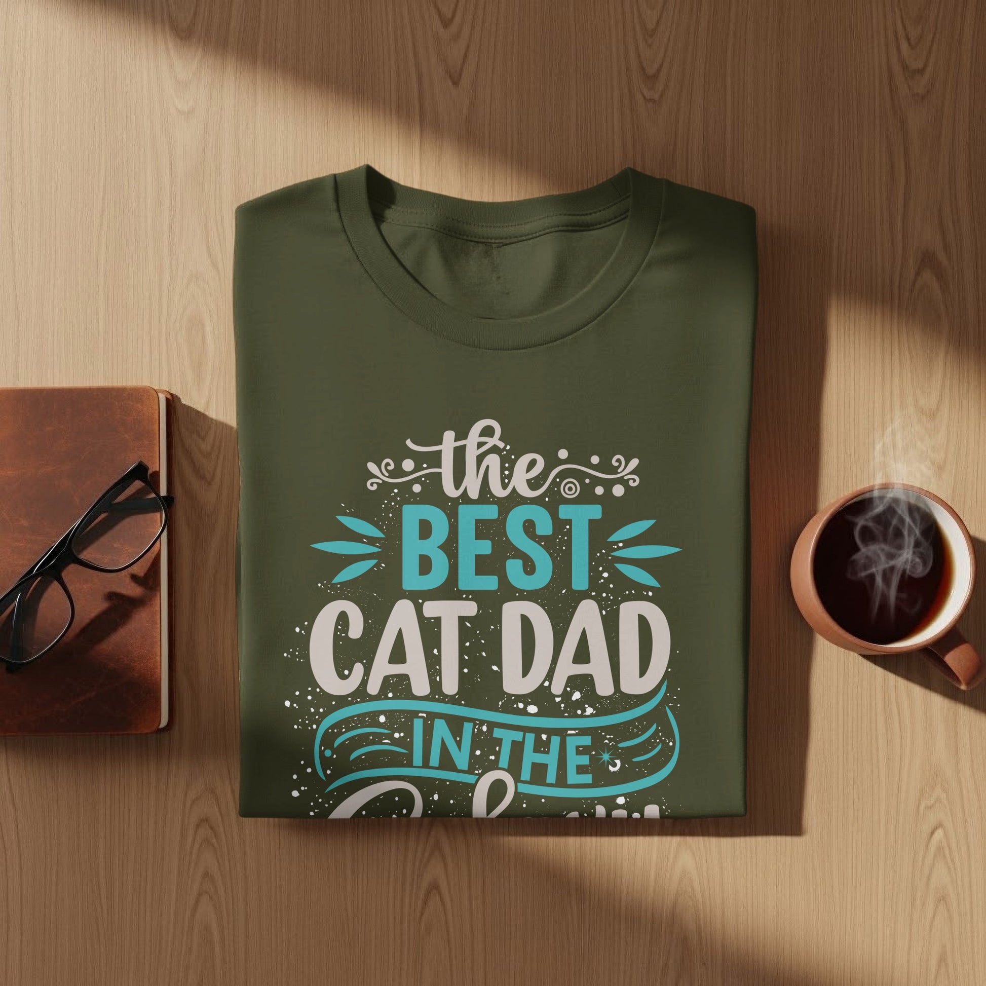 Olive green t-shirt with "The Best Cat Dad In The..." text in white and blue.