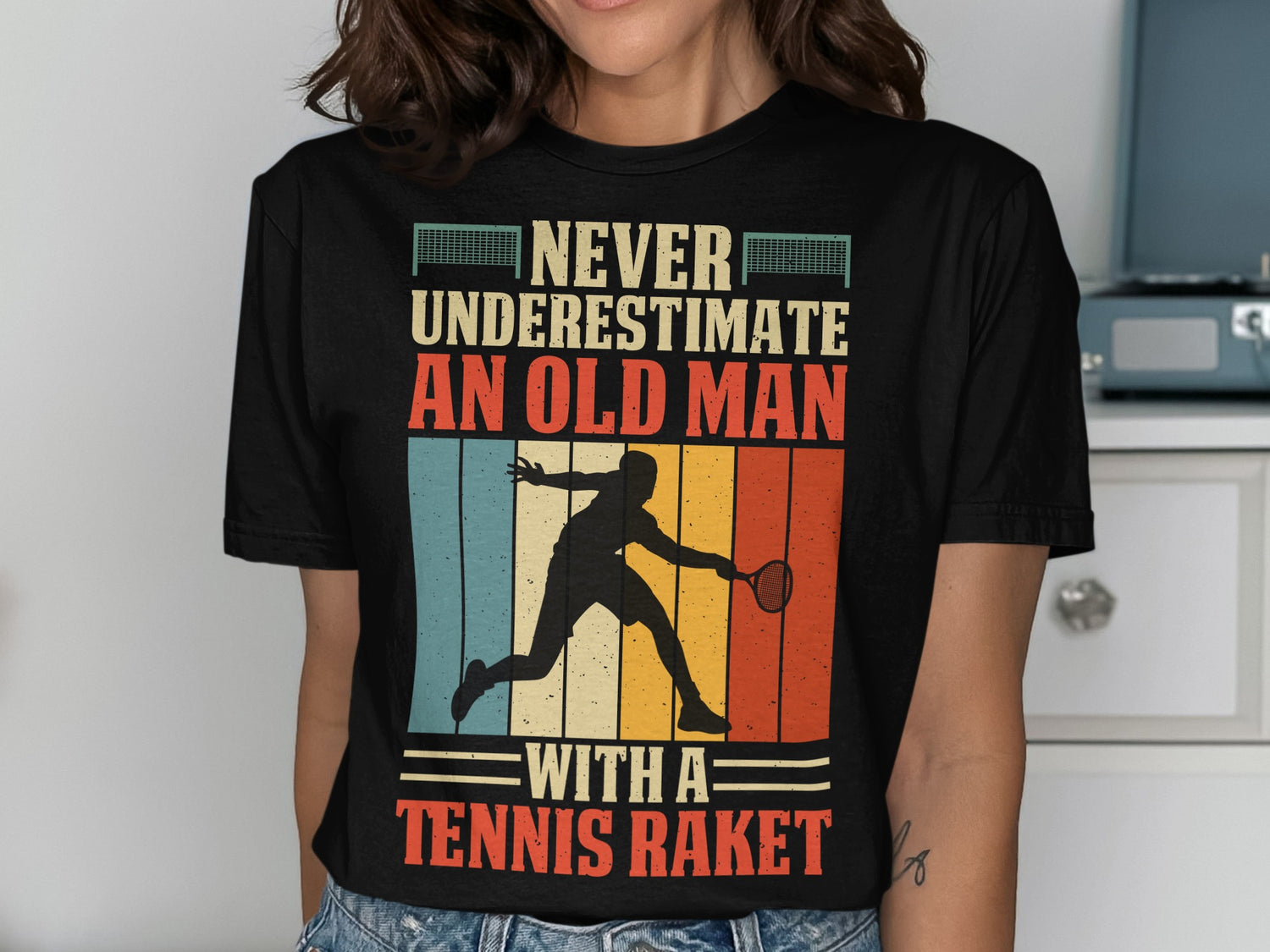 Black t-shirt with "Never underestimate an old man with a tennis racket" graphic.