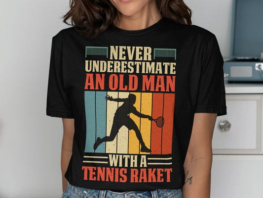 Black t-shirt with "Never underestimate an old man with a tennis racket" graphic.