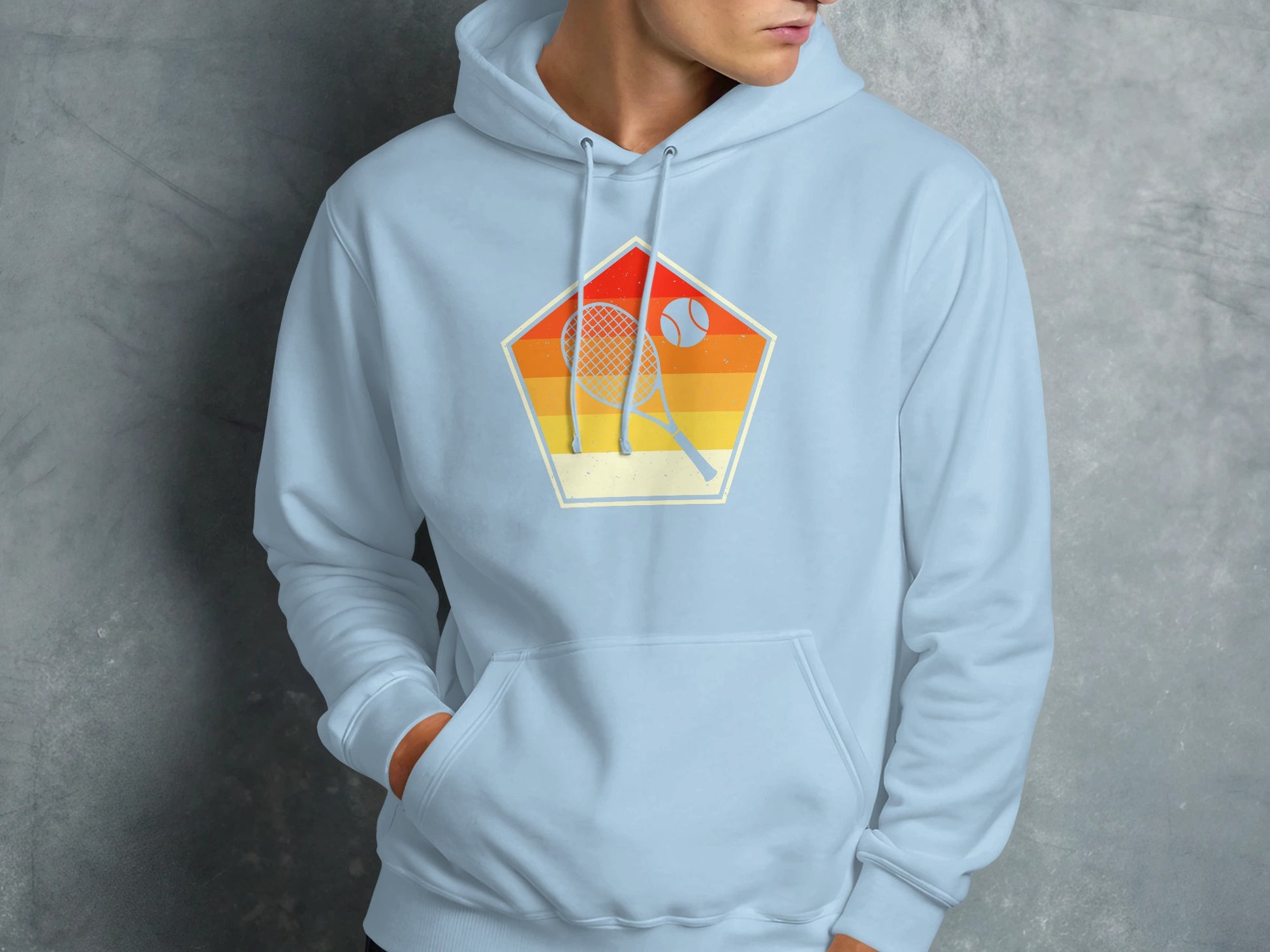 Retro pentagon graphic with tennis racket and ball on light blue hoodie.