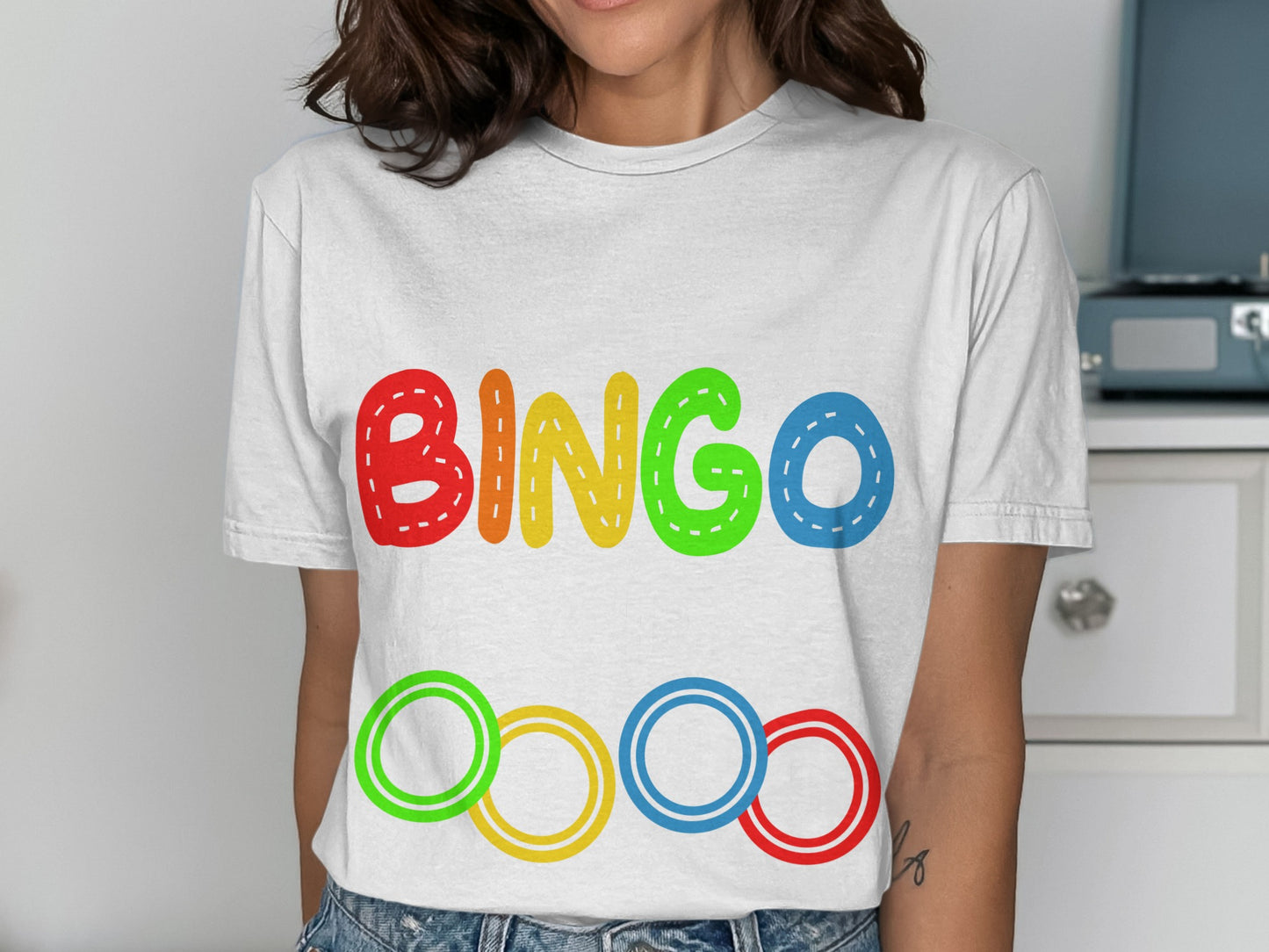 White t-shirt with colorful "BINGO" text and Olympic rings design.
