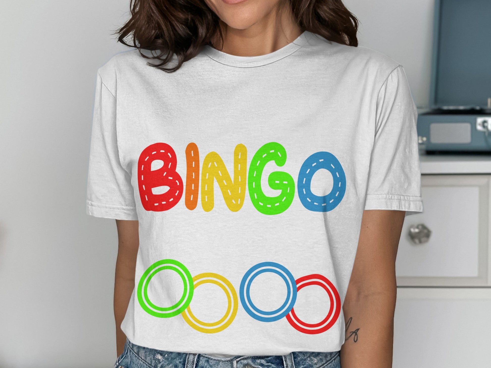 White t-shirt with colorful "BINGO" text and Olympic rings design.