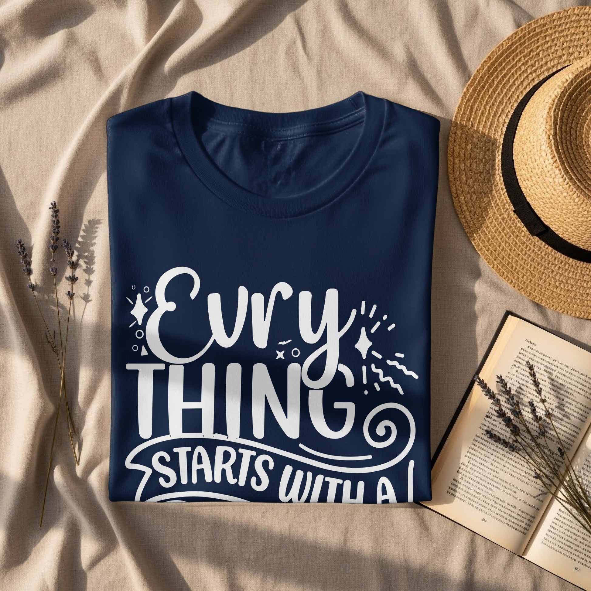 Navy t-shirt with "EvryTHING STARTS WITH A I" slogan and straw hat.